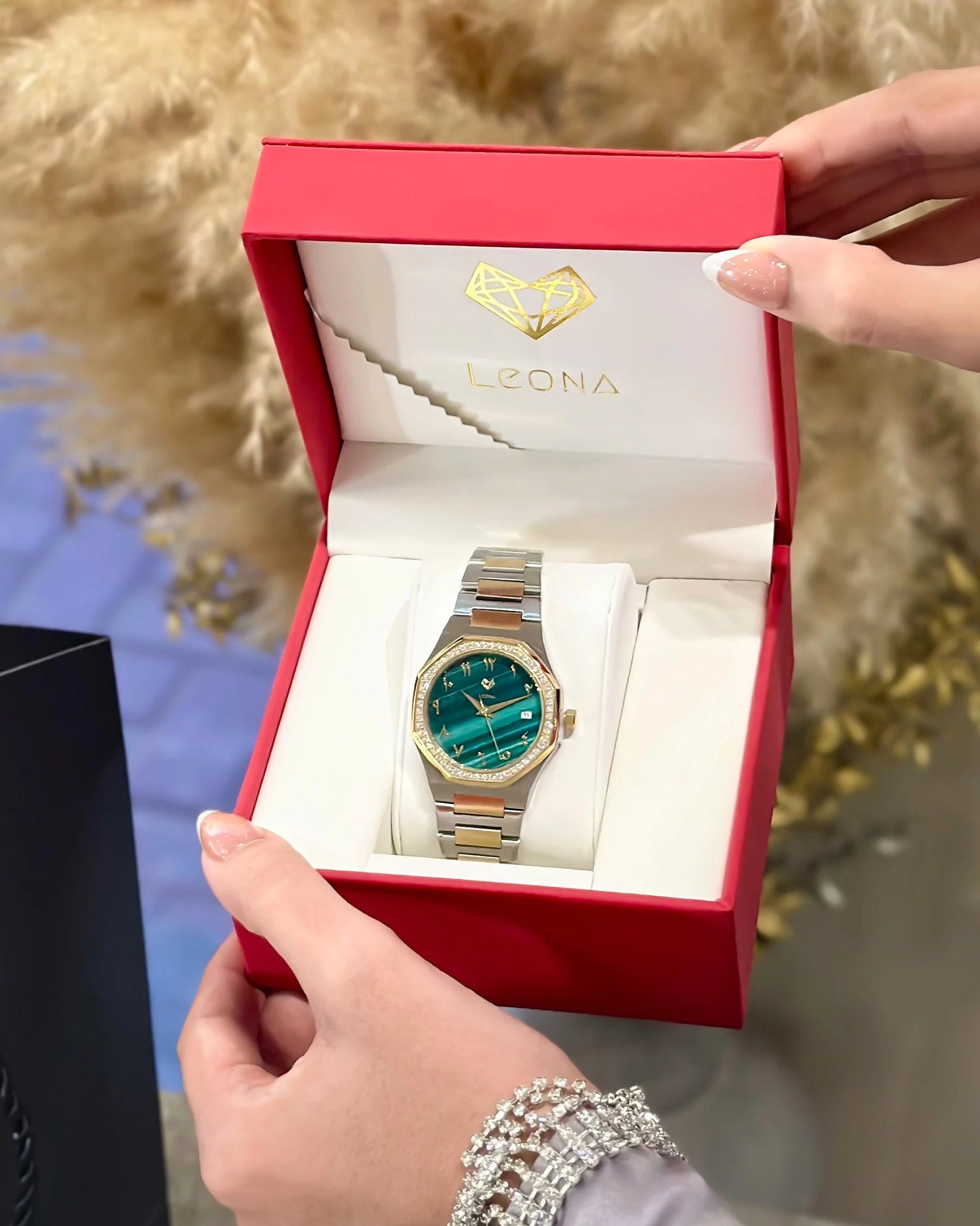 Gold and green watch in a red box with 'LEONA' branding.