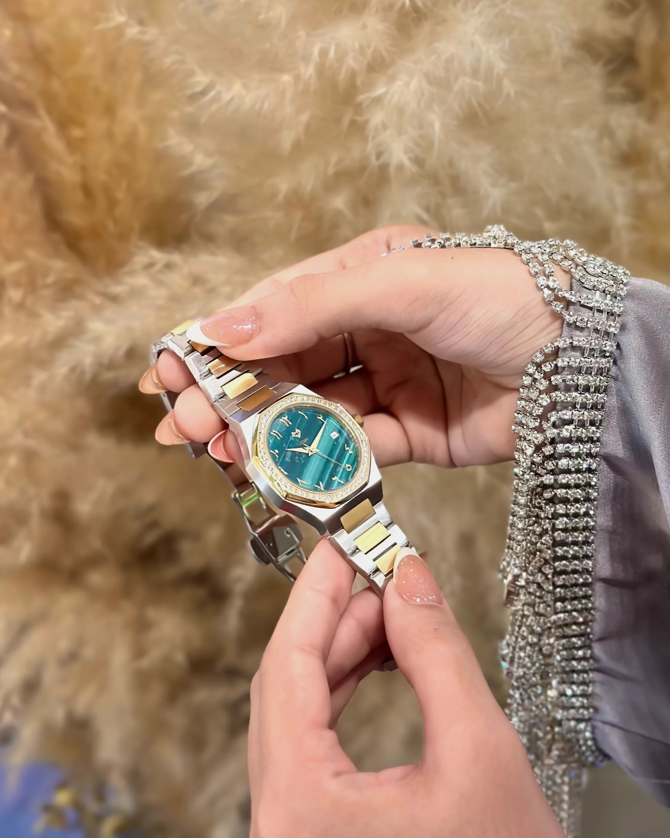 Hand holding a green watch against a textured beige background